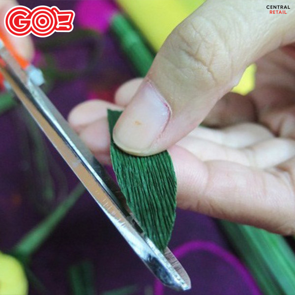 Cắt giấy nhún màu xanh thành hình lá mai và hình răng cưa để làm đài hoa