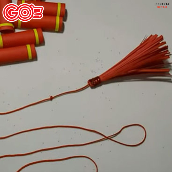 Cuộn tua rua giấy đỏ với sợi chỉ bên trong, hoàn thiện một phần của dây pháo