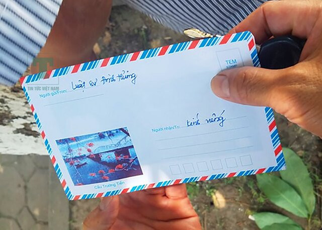 Bàn tay viết lời chia buồn trên tấm thiệp nhỏ, đặt cạnh những đóa hoa trắng trang nghiêm