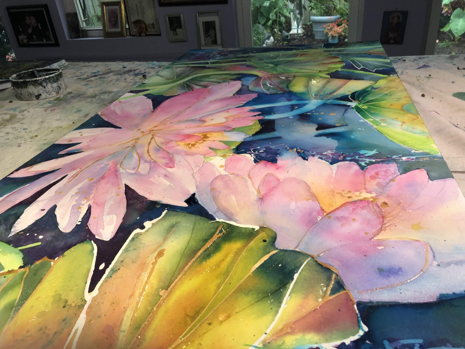 Bức tranh hoa sen đang được hoàn thiện trên bàn làm việc, minh họa quá trình gỡ masking fluid